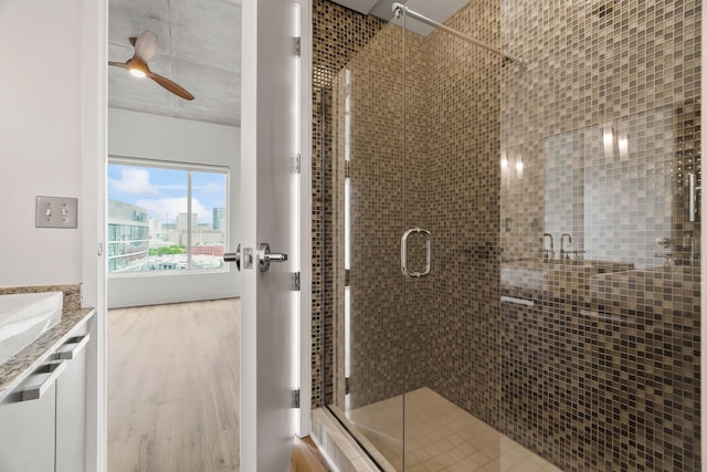 bathroom featuring a stall shower, vanity, ceiling fan, and wood finished floors