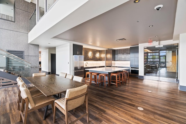 dining room with dark wood finished floors, visible vents, and a high ceiling