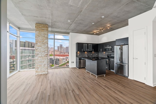 kitchen with dark countertops, a kitchen island, appliances with stainless steel finishes, wood finished floors, and dark cabinets