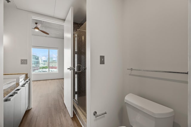 bathroom featuring vanity, wood finished floors, a stall shower, ceiling fan, and toilet