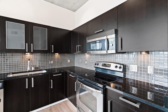 kitchen featuring backsplash, light hardwood / wood-style floors, sink, dark stone countertops, and stainless steel appliances