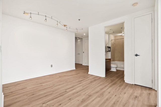 interior space featuring track lighting, light wood-style flooring, and baseboards