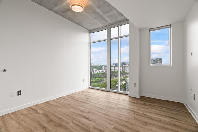 spare room featuring hardwood / wood-style flooring, a wall of windows, and a healthy amount of sunlight