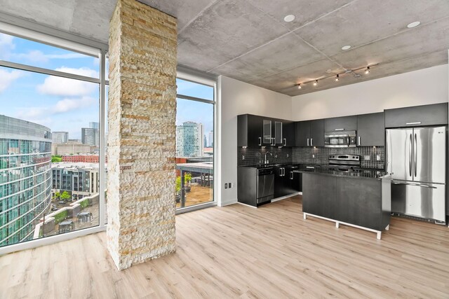 kitchen with stainless steel appliances, decorative backsplash, rail lighting, and light wood-type flooring