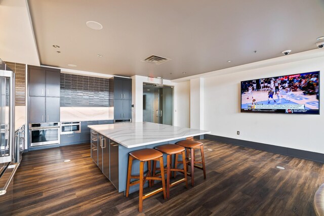 kitchen featuring tasteful backsplash, visible vents, a center island, stainless steel oven, and modern cabinets