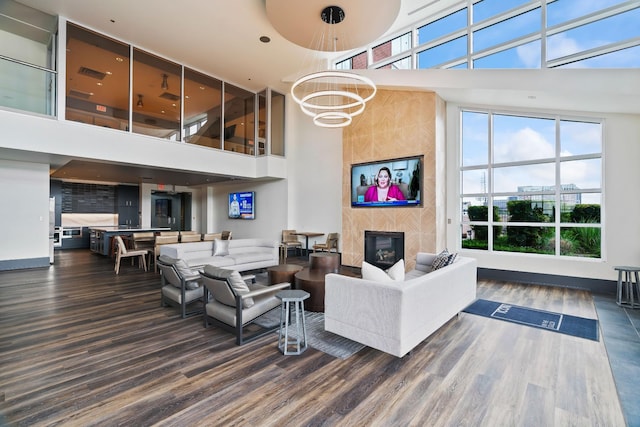 living area with a fireplace, an inviting chandelier, a high ceiling, and wood finished floors