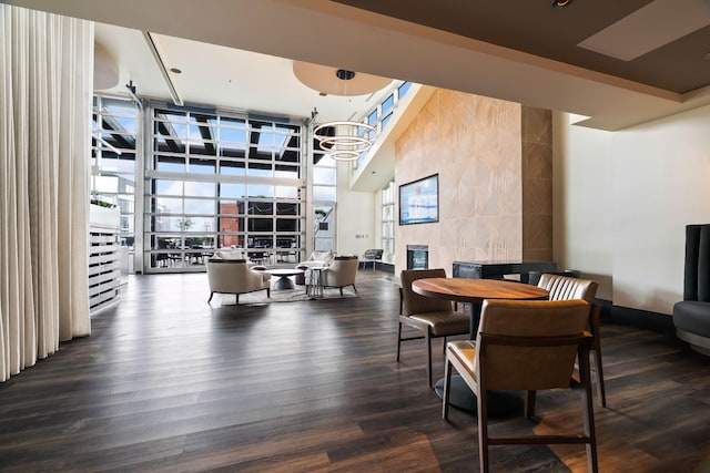 dining room featuring a fireplace, a high ceiling, baseboards, and wood finished floors