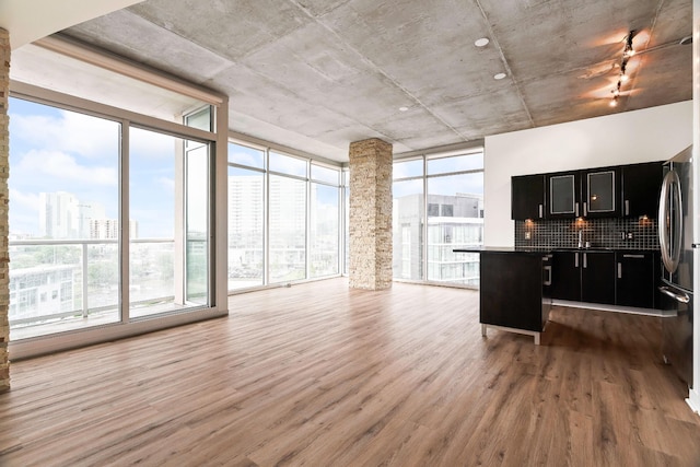kitchen with wood finished floors, open floor plan, floor to ceiling windows, freestanding refrigerator, and dark cabinets
