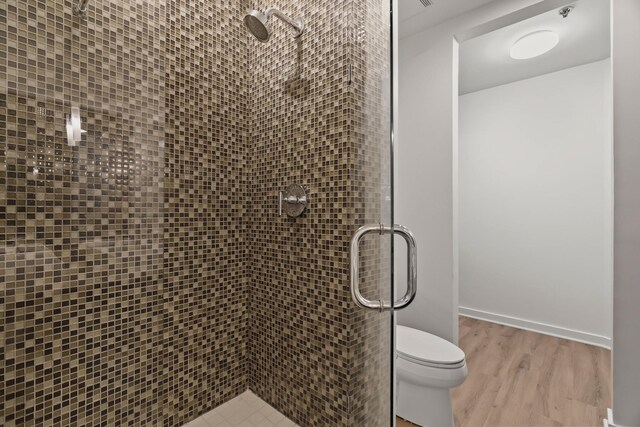 bathroom featuring wood-type flooring, toilet, and an enclosed shower