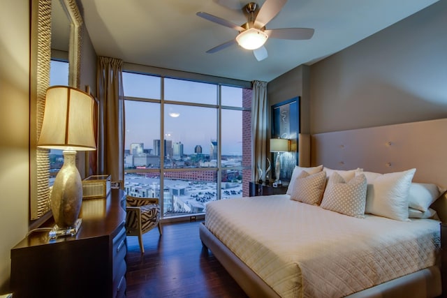 bedroom with a view of city, dark wood-style flooring, and ceiling fan