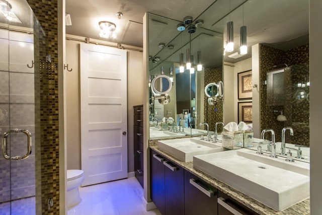 bathroom with toilet, a shower stall, double vanity, and a sink