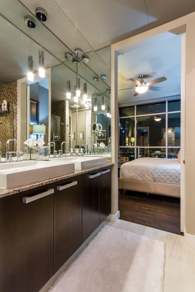 ensuite bathroom featuring ensuite bathroom, wood finished floors, a sink, a ceiling fan, and double vanity