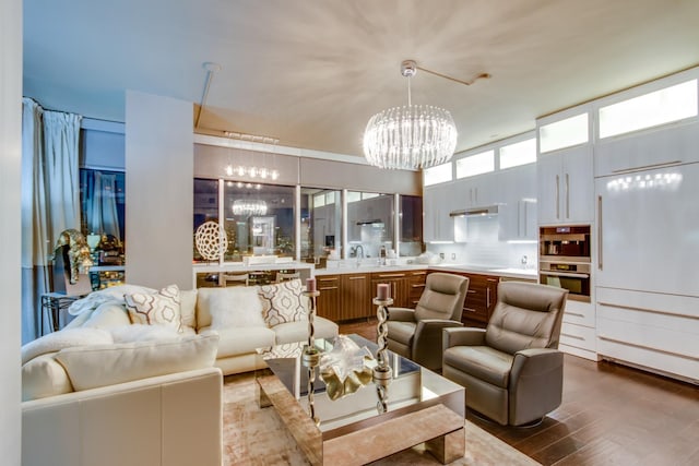 living room featuring a towering ceiling, an inviting chandelier, and dark wood-type flooring