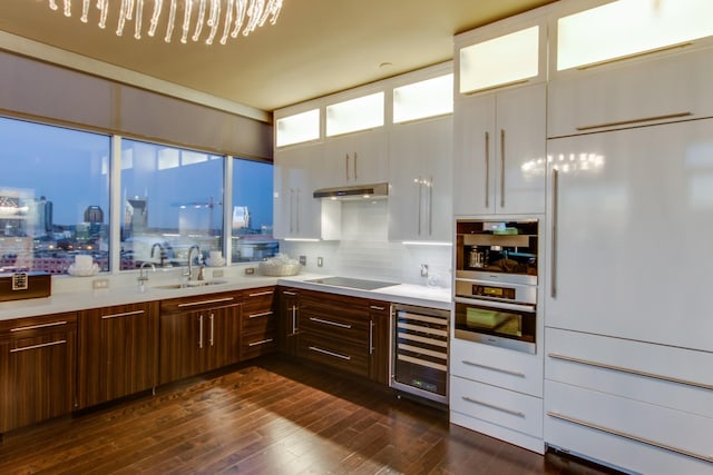 kitchen featuring wine cooler, black electric stovetop, light countertops, a sink, and under cabinet range hood