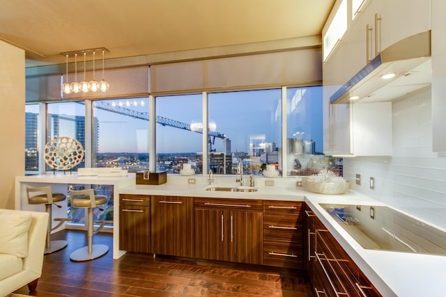 kitchen featuring dark wood-type flooring, black electric cooktop, light countertops, a city view, and a sink