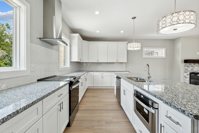 kitchen featuring sink, stainless steel appliances, plenty of natural light, and wall chimney range hood