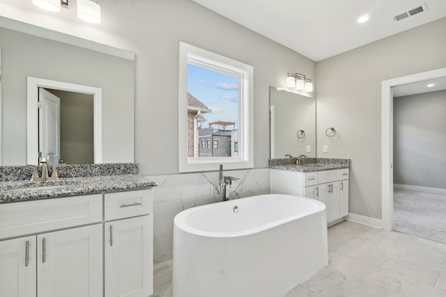 bathroom with tile patterned flooring, tile walls, a bathtub, and vanity