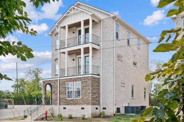 view of property exterior featuring cooling unit, a balcony, brick siding, crawl space, and board and batten siding