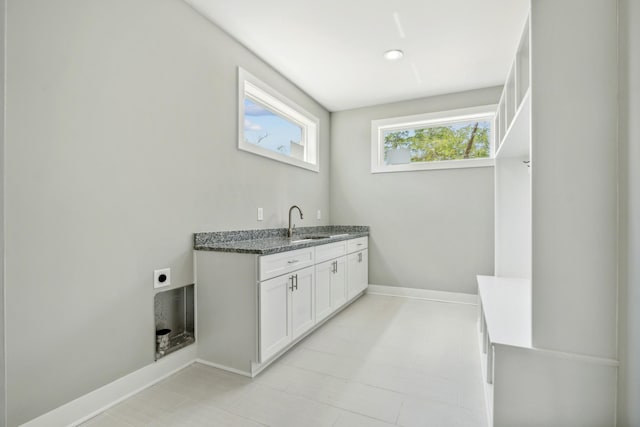 clothes washing area with a sink, electric dryer hookup, and baseboards