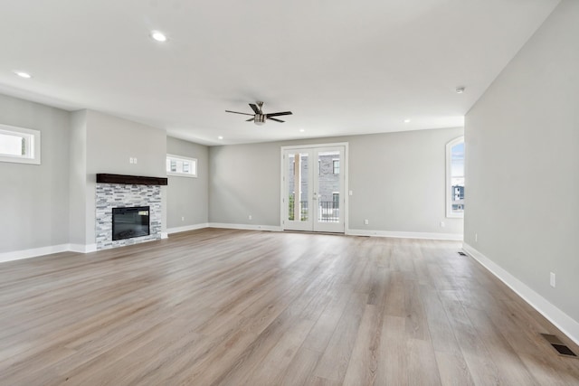 unfurnished living room with recessed lighting, visible vents, light wood-style floors, french doors, and a glass covered fireplace