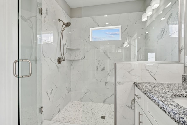 bathroom featuring a marble finish shower and vanity