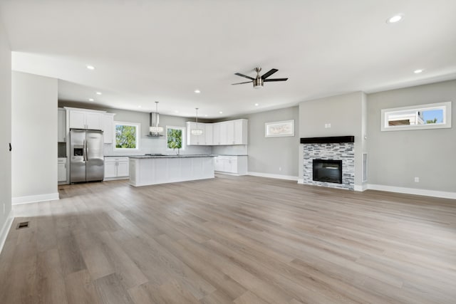 unfurnished living room with ceiling fan, a fireplace, and light hardwood / wood-style floors