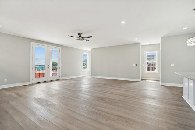 unfurnished living room with light wood finished floors, ceiling fan, a wealth of natural light, and recessed lighting