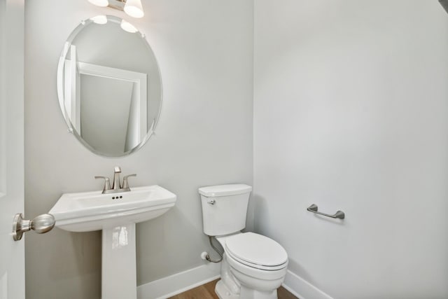 bathroom featuring a sink, wood finished floors, toilet, and baseboards