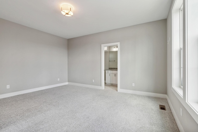 unfurnished room with light carpet, visible vents, and baseboards