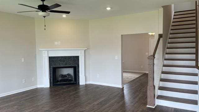 unfurnished living room with recessed lighting, dark wood-type flooring, a premium fireplace, baseboards, and stairs