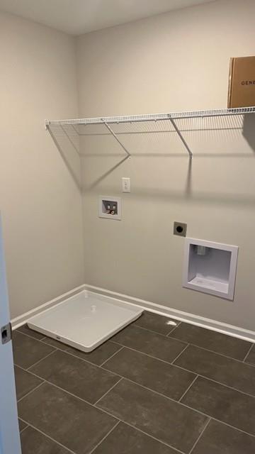 clothes washing area featuring hookup for a washing machine, electric dryer hookup, laundry area, dark tile patterned floors, and baseboards