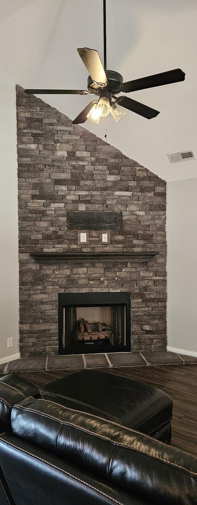 interior details featuring ceiling fan, a stone fireplace, and wood-type flooring