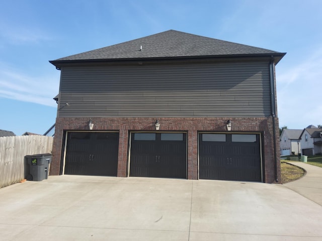 view of side of home with driveway, fence, and brick siding