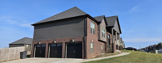 view of side of home featuring driveway, brick siding, a lawn, and fence