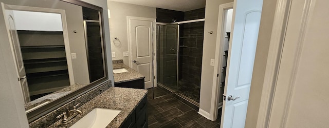 bathroom with two vanities, a sink, a spacious closet, and a shower stall