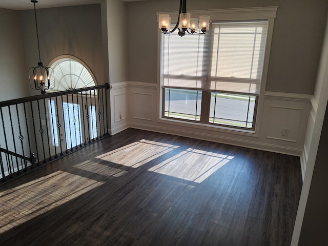 spare room with dark wood-type flooring and an inviting chandelier