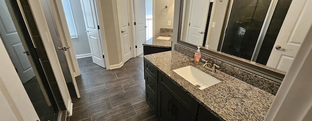 full bath with a stall shower, vanity, and baseboards