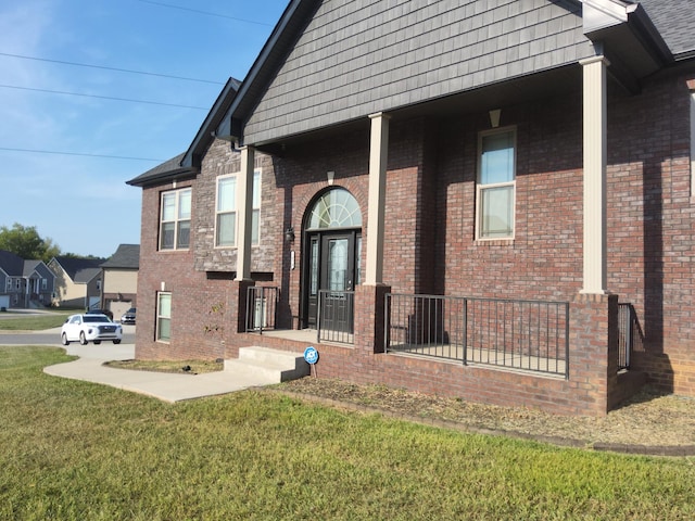 property entrance with brick siding and a yard