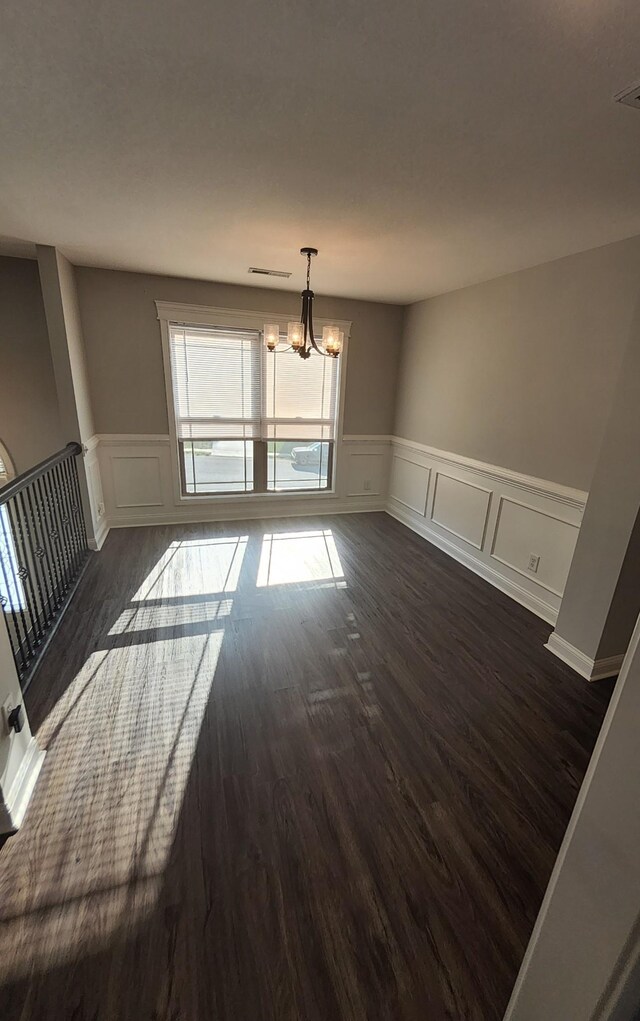 unfurnished room featuring dark hardwood / wood-style floors and a chandelier