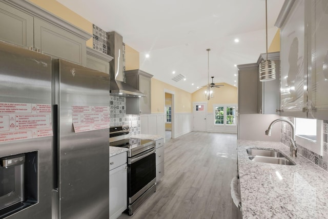 kitchen with visible vents, wainscoting, wall chimney exhaust hood, appliances with stainless steel finishes, and a sink