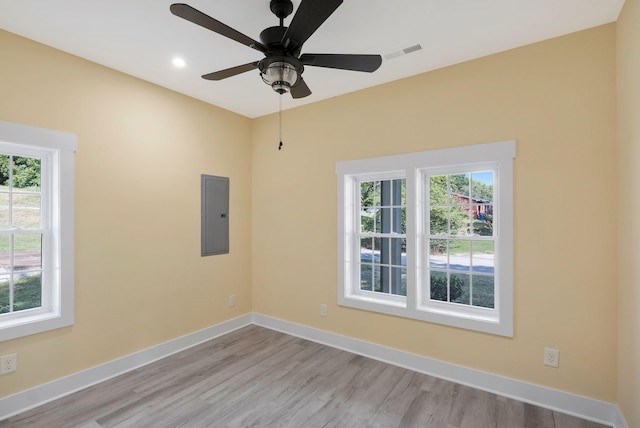 unfurnished room with a healthy amount of sunlight, electric panel, baseboards, and wood finished floors