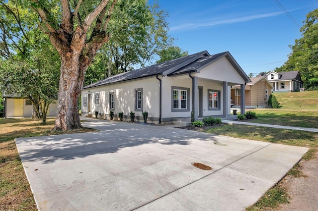 view of front of house featuring concrete driveway, covered porch, a front lawn, and stucco siding