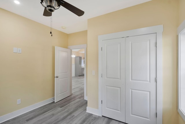 unfurnished bedroom featuring a closet, light wood-type flooring, a ceiling fan, and baseboards