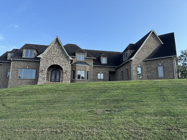 french country style house featuring a front yard and brick siding