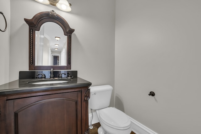 bathroom featuring toilet, vanity, and baseboards