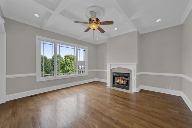 unfurnished living room with a tiled fireplace, beamed ceiling, coffered ceiling, dark wood-type flooring, and ceiling fan