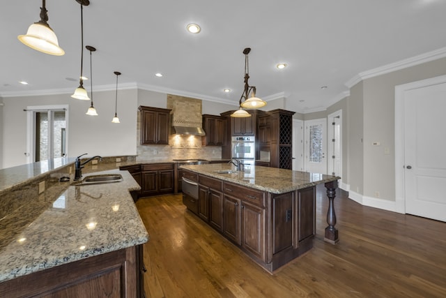 kitchen featuring light stone countertops, a large island with sink, and sink