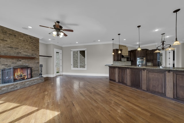 kitchen featuring open floor plan, hanging light fixtures, oven, and dark brown cabinetry