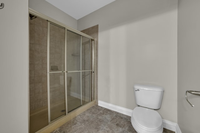 full bath featuring a stall shower, baseboards, toilet, and tile patterned floors