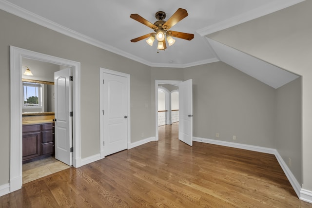 interior space featuring ornamental molding, light hardwood / wood-style flooring, ensuite bath, ceiling fan, and vaulted ceiling